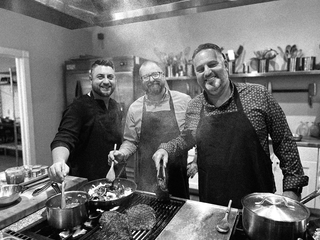 Close up of the hands of three guests cooking at The Recipe. 