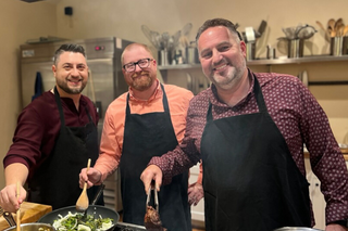 Three male guests cooking at the stovetop in The Recipe kitchen.